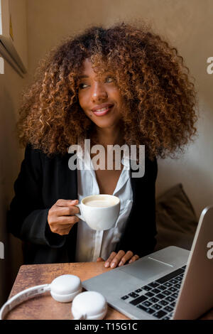 Junge Frau mit Laptop in einem Cafe, trinken einen Kaffee Stockfoto