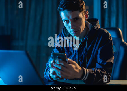 Ein junger Mann auf einem Laptop in der Nacht arbeiten. Der Entwerfer oder Systemadministrator waren spät in der Arbeit. Stockfoto