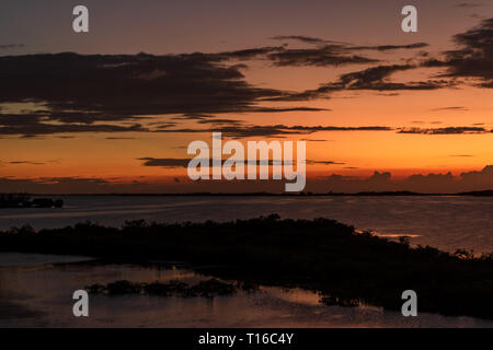Die Sonne über Chetumal Bay vor Ambergris Caye, Belize casting brillante Farbtöne über den Himmel und in den Gewässern durch eine warme Brise gekräuselte Wellen reflektiert. Stockfoto