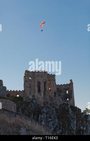 Para Glider über zerstörte Burg auf dem Felsen fliegen. Motorsegler über mittelalterliche Architektur. Stockfoto