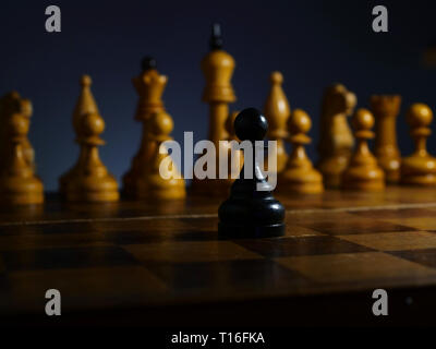 Brave ambitionierte Geschäftsmann und Herausforderung. Schwarze hölzerne Spielfigur und weiß Schach. Stockfoto