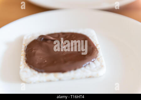 Nahaufnahme von Reis Kuchen mit Schokolade Haselnuss mit brauner Sirup vegan Vegetarische snack Dessert ein einziges Stück auf weiße Platte Stockfoto