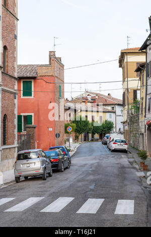 Chiusi, Italien - 25 August 2018: leere Straße in kleinen Stadt Dorf in Umbrien bei Tag mit Autos von bunten stein Architektur geparkt Stockfoto