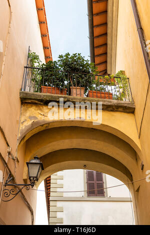 Chiusi, Italien Straße in kleinen mittelalterlichen Stadt Dorf in Umbrien während der sonnigen Tag mit niemand orange gelb leuchtenden bunten Wänden und Arch arch Stockfoto