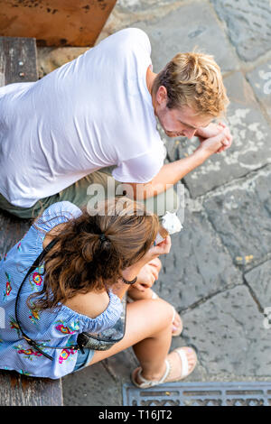 Montalcino, Italien - 26 August, 2018: Die hohen Winkel Luftaufnahme von Menschen paar essen Eis gelato Kegel Sorbet auf Quadrat in kleinen historischen mittelalterlichen Stockfoto