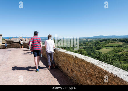 San Gimignano, Italien - 27. August 2018: Paar Menschen zu Fuß Sehenswürdigkeiten kleine historische mittelalterliche Dorf in der Toskana im Sommer Tag mit Gebäuden Stockfoto