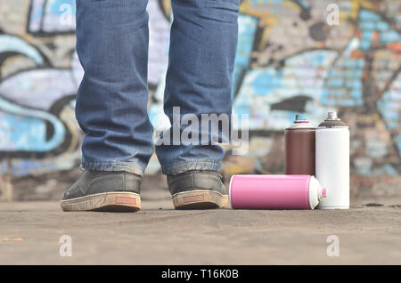 Eine Fotografie aus einer bestimmten Anzahl von sprühdosen vor dem Hintergrund der Raum mit der Wand, an der sich der junge Mann zieht eine große Graffiti drawin Stockfoto