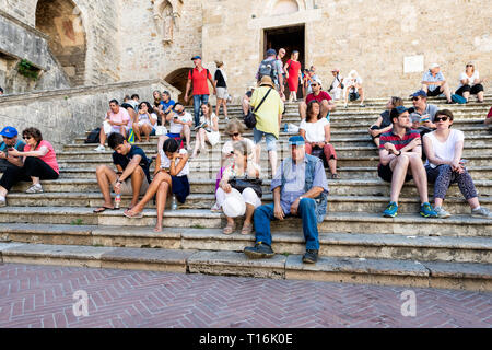 San Gimignano, Italien - 27. August 2018: Viele Leute sitzen, die sich auf Schritte in kleinen mittelalterlichen Stadt Dorf in der Toskana im Sommer Tag Stockfoto