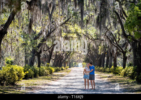Straße Straße Landschaft mit Eichen Pfad in Savannah, Georgia, berühmten Bonaventure cemetery mit spanischem Moos und junge glücklich romantisches Paar stehend Stockfoto