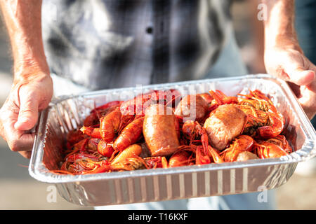 Nahaufnahme von Hummer und Meeresfrüchte mit Händen hält Tablett mit roten Schalentiere in New Orleans Street Food Stockfoto