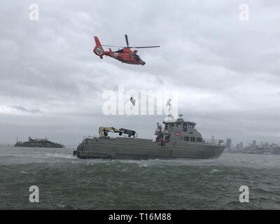 Coast Guard Explosive Detection canine Handler von Sicherheit und Gefahrenabwehr im Seeverkehr Team 91105 in Alameda, Kalifornien, und das Bodenpersonal in die Mitglieder von Air Station San Francisco Verhalten canine hoist Operationen mit Besatzungsmitglieder aus der Army Corp der Ingenieure Donald A.B. Dillard in der San Francisco Bay, 22. März 2019. Die canine Handler von Msst 91105 Zug häufig in anspruchsvollen Umgebungen, um sicherzustellen, dass Sie immer bereit sind, bereitstellen, wann immer sie benötigt werden. U.S. Coast Guard Foto von Petty Officer 2nd class John neilson. Stockfoto