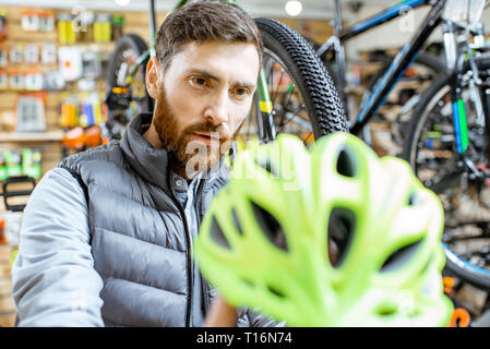 Man Kontrolle der Qualität einer neuen Schutzhelm im Fahrrad Shop Stockfoto