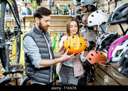 Der Mann und die Frau der Wahl Schutzhelm für die Fahrt mit dem Fahrrad gemeinsam am Fahrrad Shop Stockfoto