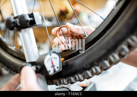 Mann ausrichten Fahrrad Rad tensing Speichen mit einem speziellen Schlüssel am Arbeitsplatz des Workshops, Nahaufnahme Stockfoto