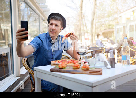Allein touristische Mann unter selfie und essen ein Stück Pizza auf italienische Restaurant Stockfoto