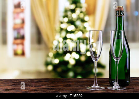 Champagner in ein Glas und eine Flasche auf einen unscharfen Hintergrund einer Weihnachtsbaum. festliche Hintergrund. Platz für Text Stockfoto