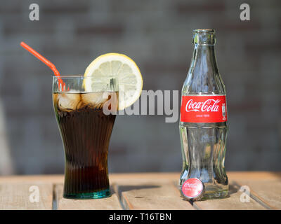 HOEILAART, Belgien - 17. MAI 2017: Eine gegossen Cola Flasche neben eine Cola Glas mit Eiswürfel und eine Zitronenscheibe gefüllt. Stockfoto