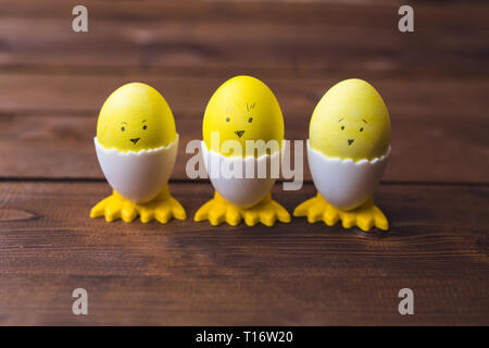 Lustige gelbe Ostereier mit verschiedenen Gesichtern und Füße auf hölzernen Hintergrund Stockfoto