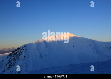 Die ersten Strahlen der Sonne die Spitze des Berges zu beleuchten. Karpaten, Winter. Stockfoto