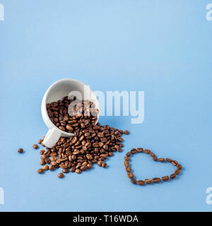 Kreative Valentinstag Konzept Foto Tasse Kaffee mit Liebe urlaub Feier Herz aus Bohnen auf blauem Hintergrund. Stockfoto