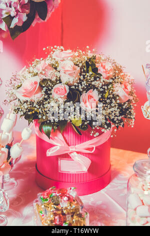 Candy Bar. Helle Einrichtung in Weiß mit rosa Blüten. Rosa Pulver. Blumenstrauß aus zarten rosa Blüten in runde Schachteln. Treppen und Stuhl auf dem Stockfoto