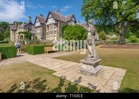 Klassische Statue in Richtung Bodnant Halle und zwei Besucher, Bodnant Garden, Conwy, Wales, Vereinigtes Königreich, Stockfoto