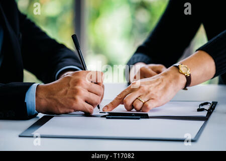 Seitenansicht des Ernteguts Geschäftsfrau, die auf Vertrag Geschäftsmann mit Stift am Tisch im Büro Stockfoto