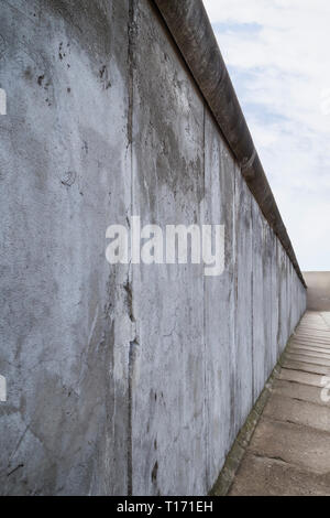 Seitliche Sicht auf einen Abschnitt der Berliner Mauer an der Gedenkstätte Berliner Mauer (Berliner Mauer) in Berlin, Deutschland, an einem bewölkten Tag. Stockfoto