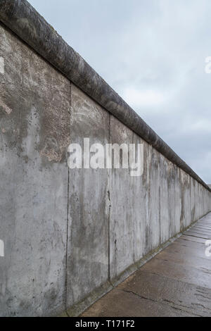 Seitliche Sicht auf einen Abschnitt der Berliner Mauer an der Gedenkstätte Berliner Mauer (Berliner Mauer) in Berlin, Deutschland, an einem bewölkten Tag. Stockfoto