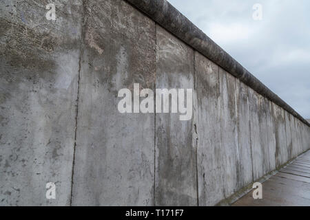 Seitliche Sicht auf einen Abschnitt der Berliner Mauer an der Gedenkstätte Berliner Mauer (Berliner Mauer) in Berlin, Deutschland, an einem bewölkten Tag. Stockfoto