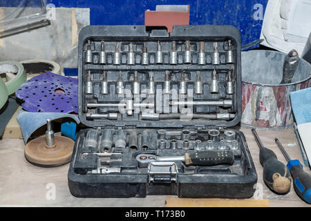 Dirty Tools in einer Box mit Drehmomentschlüssel und verschiedene Anbaugeräte zum Aufschrauben auf eine Werkbank nach einem Arbeitstag in einem Auto und Fahrzeug Werkstatt. Stockfoto
