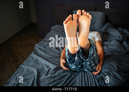 Bild der Mann lag auf dem Bett und zeigt beide Füße auf die Kamera. Haut sind gesund und sauber. Der Mensch ist in Bedoom. Er trägt Schlafanzug. Stockfoto