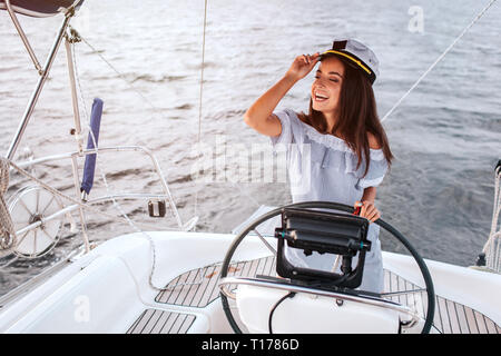 Schönes Modell steht vor der Ruder und verwendet sie. Sie hält die Hand, die in den Deckel und nach links schauen. Frau ist ruhig und friedlich. Sie ist glücklich. Stockfoto