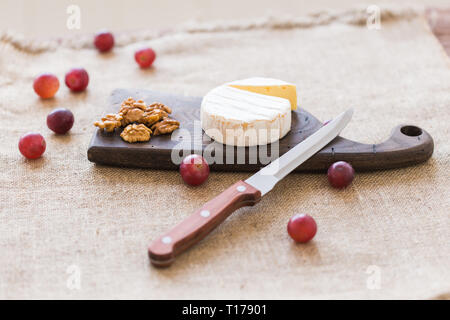 Brie Käsesorte. Camembert. Frische Brie Käse auf einem Holzbrett mit Nüssen und Trauben. Italienischen, Französischen Käse. Stockfoto