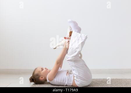 Menschen, Kinder und Haustiere Konzept - kleines Kind Mädchen auf dem Boden liegend mit niedlichen Welpen Jack Russell Terrier Stockfoto