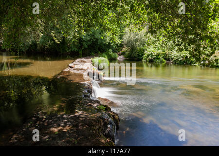 Kristallklares Wasser, kleinen Wasserfällen, wenn man durch die künstlichen Damm, der in einem Fluss in Portugal. Stockfoto