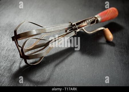 Alte hand Schneebesen auf einem Schwarzen Tisch. Stockfoto