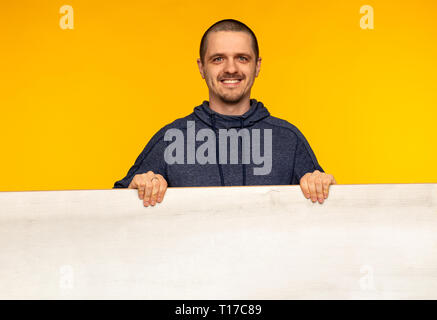 Lächelnder Mann mit hölzernen weißen leeren Brett in den Händen Stockfoto