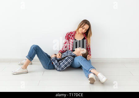 Familie, Muttertag und Teenager Begriff - Portrait von Mutter und Sohn sitzen auf dem Boden Stockfoto