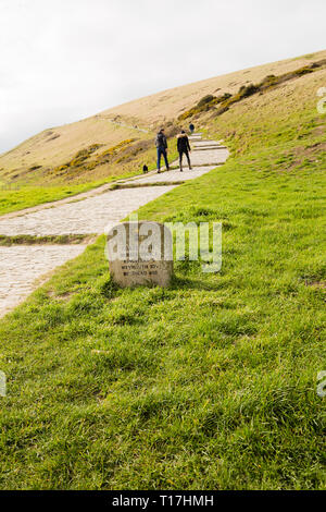 Küstenweg zwischen Lulworth Cove, und Durdle Dor Übersicht Stein unterzeichnen. Es sind zwei Personen gesehen zu Fuß in der Ferne. Stockfoto