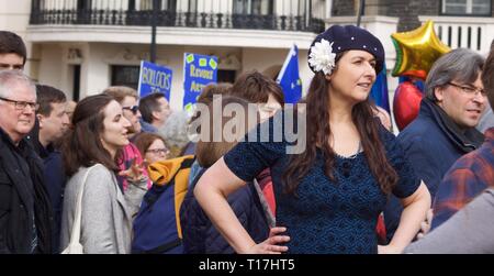 Junge Frau auf den Hüften bleiben im März in London tragen Barett mit weiße Blume Stockfoto