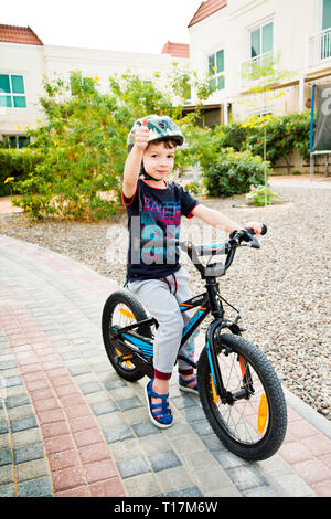 Kleiner Junge, der dich wissen lässt, dass er gut ist, mit Daumen nach oben in die Luft zu gehen, um auf diesem Fahrrad losgehen. Stockfoto