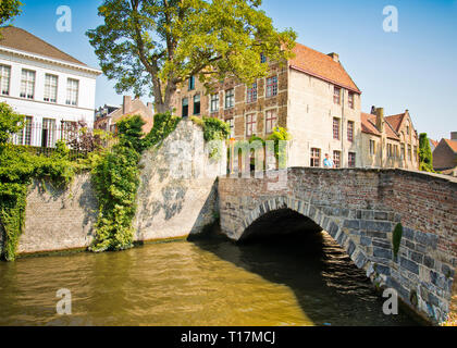 Frau allein auf alten malerischen Brücke über den Kanal mit historischen traditionellen Häusern im Hintergrund. Brügge Altstadt. Stockfoto