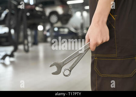 Nahaufnahme von Mechaniker hand Schlüssel, Spezialwerkzeuge für die Reparatur und zur Festsetzung von Fahrzeugen. Mann in Overalls in Autoservice. Stockfoto