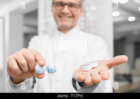 In der Nähe der Behälter für Kontaktlinsen. Auge specialict im weißen Mantel und Gläser in der medizinischen Zimmer Holding, die Behälter für Kontaktlinsen. Augenarzt Konzept. Stockfoto