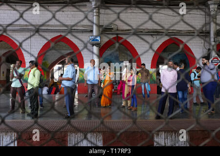 Blick durch die Gitter Draht vor einem personenzug Phantom Fenster in Mumbai, Indien, in Richtung der Plattform Byculla Station und Passagiere Stockfoto