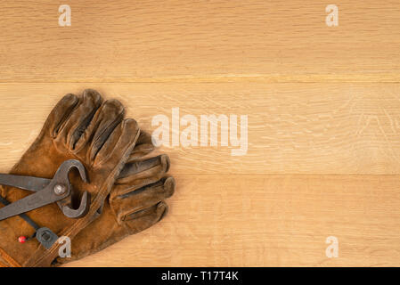 Jahrgang Paar lange Griff Seitenschneider Zangen und gut getragen Leder Arbeitshandschuhe Holz Hintergrund Kopie Raum Stockfoto