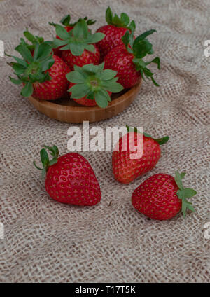 Reife Erdbeeren in eine hölzerne Schüssel, und auf sack Oberfläche Stockfoto