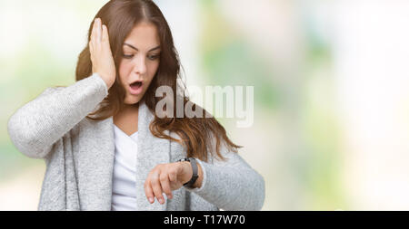 Schöne Übergrößen junge Frau tragen Winter Jacke über isolierte Hintergrund ein Blick auf die Uhr Zeit Sorgen, Angst, sich spät Stockfoto