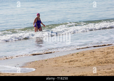 Bournemouth, Dorset, Großbritannien. 24. Mär 2019. UK Wetter: schöner sonniger Tag mit blauen Himmel und warmen Sonnenschein am Bournemouth Strände, die Besucher des Seaside Kopf Die meisten Wetter zu machen. Ältere Frau zu Fuß aus dem Meer nach einem Bad im Meer. Credit: Carolyn Jenkins/Alamy leben Nachrichten Stockfoto